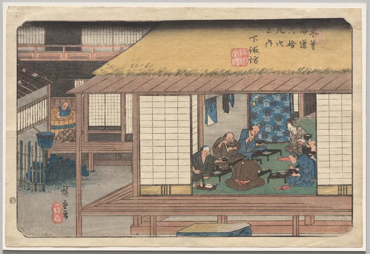 Japanese woodblock print showing travelers resting and eating together inside an open-front wooden inn along the Kisokaido highway